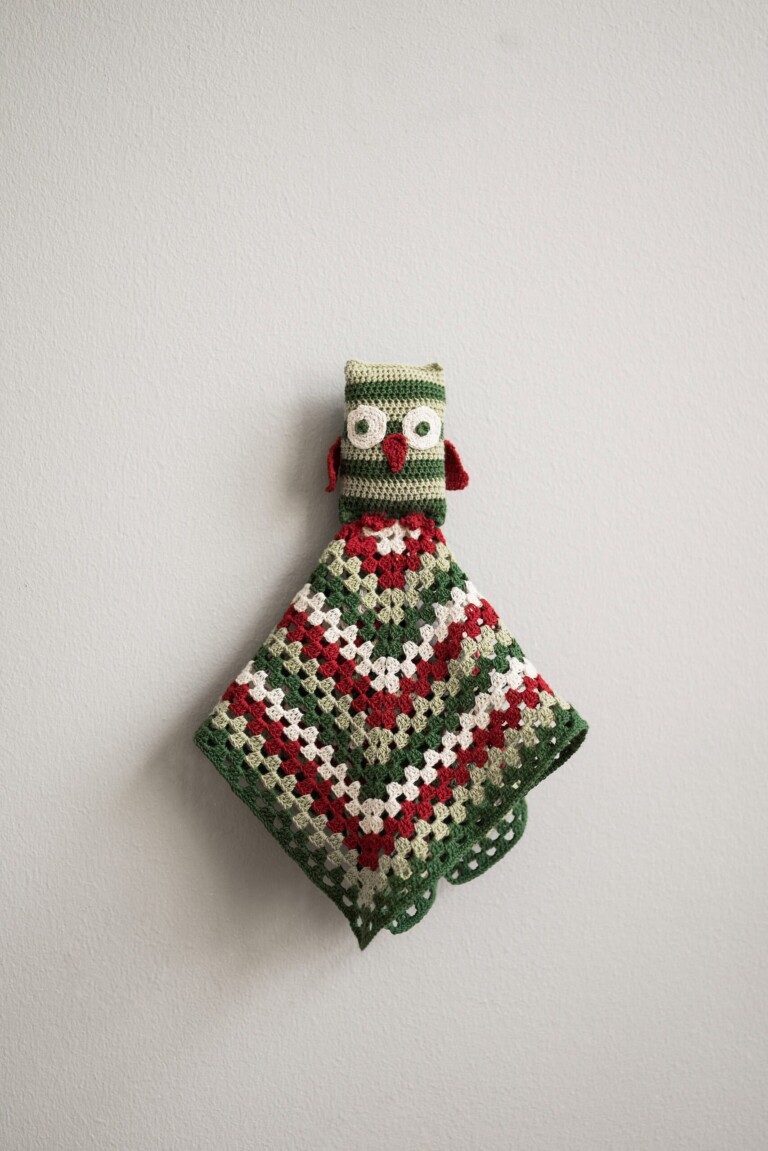 Käsin virkattu Pöllö-unikaveri koriste vihreillä, valkoisilla ja punaisilla siksak-raidoilla.