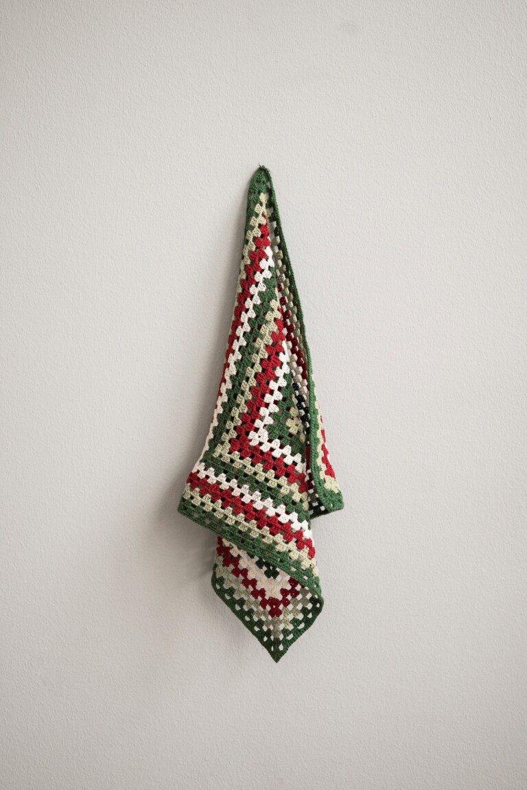 Värikäs virkatty Pöllö-unikaveri seinällä, koristeltuna vihreällä, punaisella ja luonnonvalkoisella langalla.
