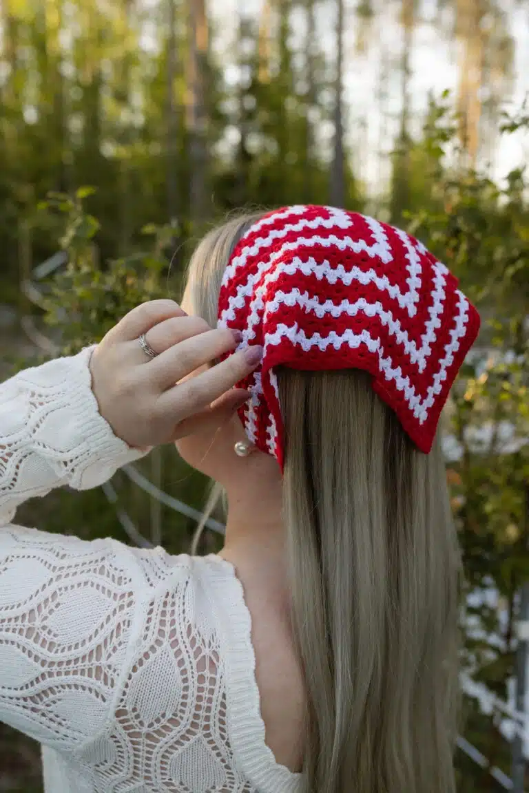 Punavalkoinen hilkka-bandana pitkätukkaisen henkilön päässä metsässä.