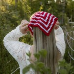 Punavalkoinen Hilkka-bandana ja luonnonvalkoinen palmikkoneule metsässä.