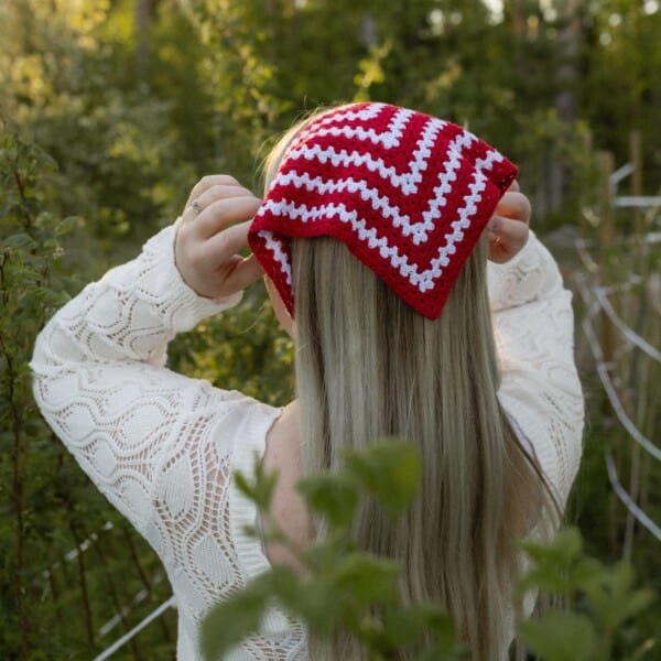 Punavalkoinen Hilkka-bandana ja luonnonvalkoinen palmikkoneule metsässä.