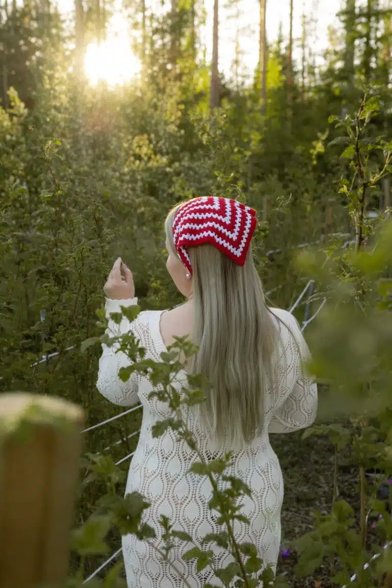 Nainen metsässä, yllään punavalkoinen Hilkka-bandana ja vaalea paita.