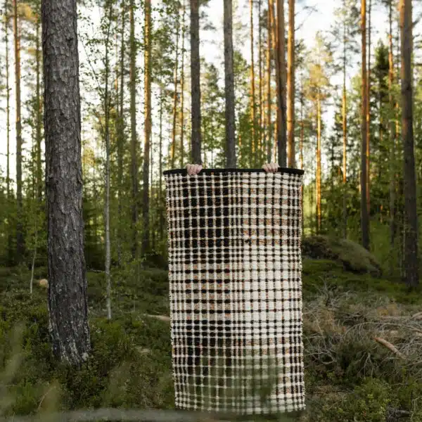 Ruutukuvioinen Ruutuleikki-matto mäntymetsässä sammaleisen metsän keskellä.