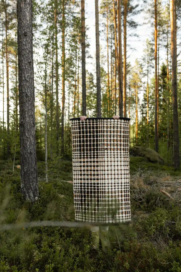 Ruutukuvioinen Ruutuleikki-matto mäntymetsässä sammaleisen metsän keskellä.