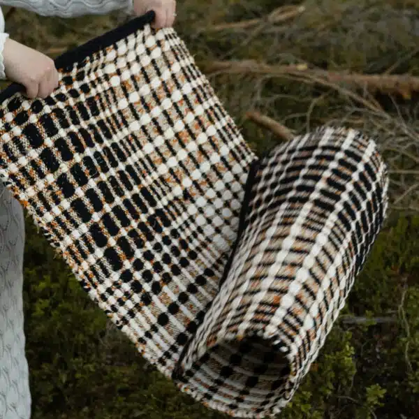 Ruutuleikki-matto levitetään metsässä, ja sen ruudullinen kuvio korostuu luonnon keskellä.