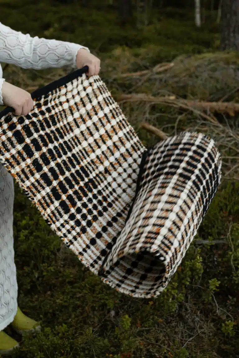 Ruutuleikki-matto levitetään metsässä, ja sen ruudullinen kuvio korostuu luonnon keskellä.